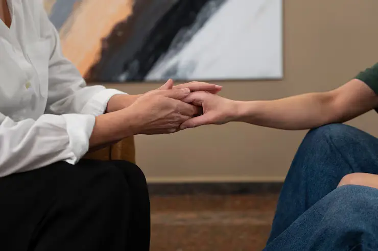 One person hold the hand of other person for counselling