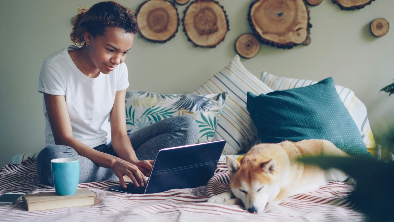 women working on laptop and dog sitting besides